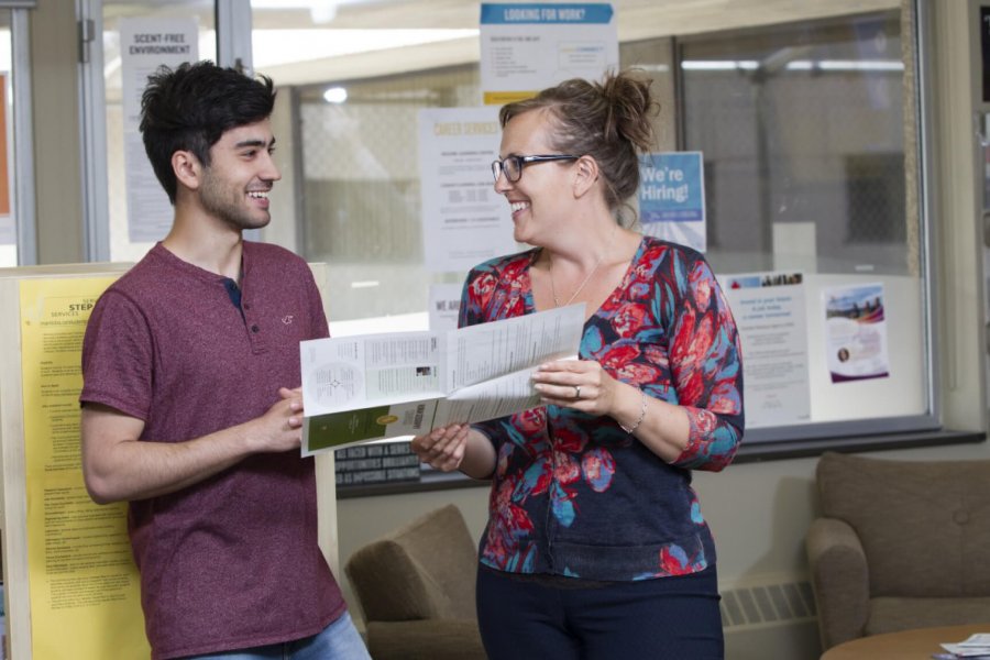 An academic advisor reviews a career compass brochure with a student. 