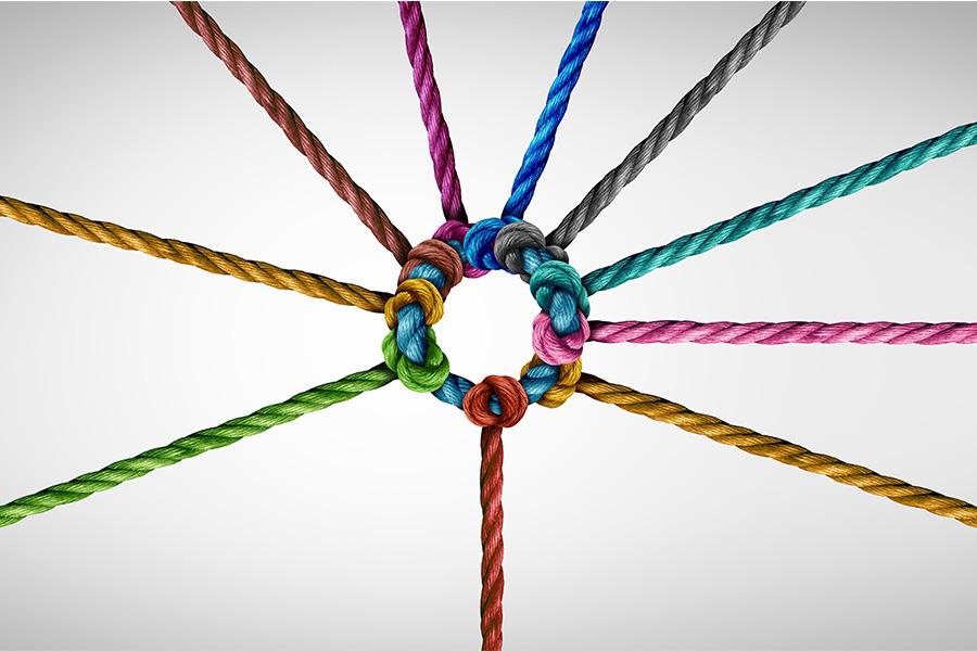 A circle formed by the ends of multiple colored ropes knotted together, radiating outward against a plain background.