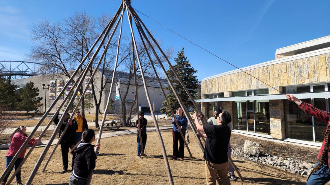 A group of people setting up a tipi.