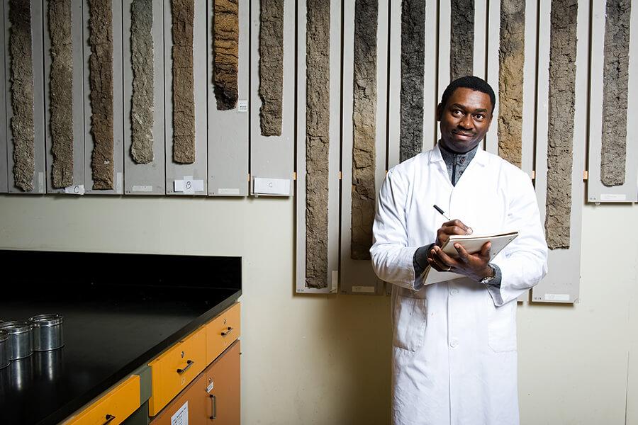 A student looking at fossil samples wearing a lab coat.