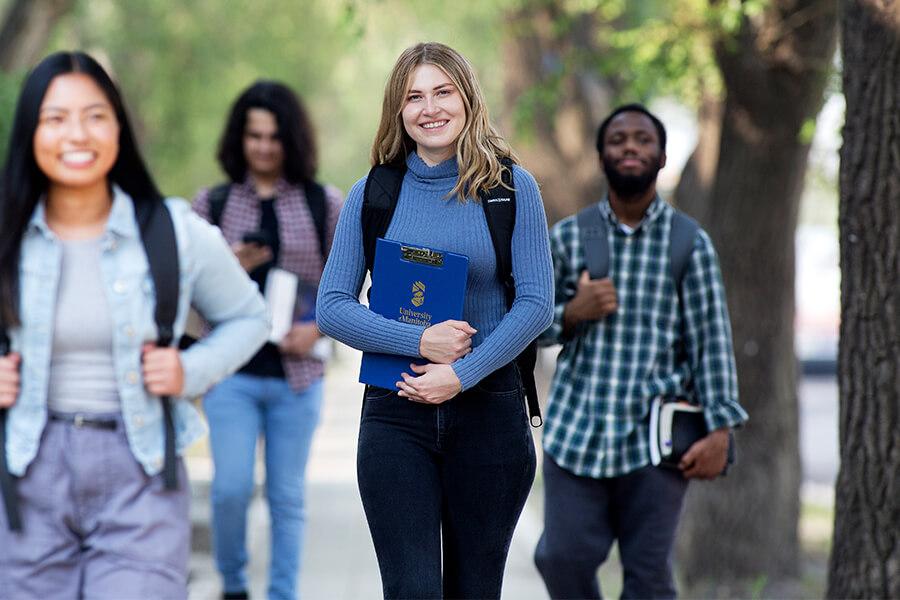Students walking along an outdoor path surrounded by trees.