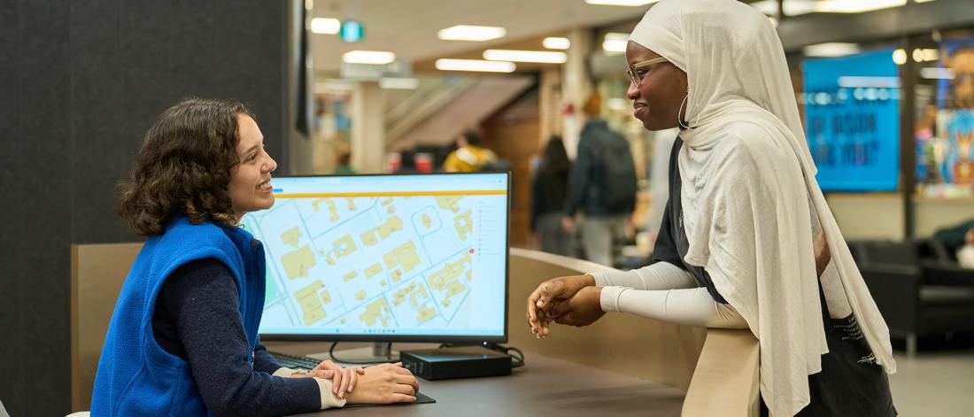 An image of a student asking for directions at the Student Affairs Connection Desk. 