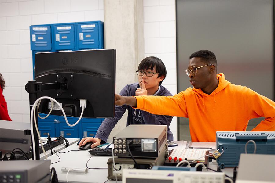 Image of two male students working together in a computer lab.