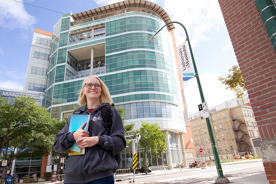 Image of a female student in front of a modern glass building.