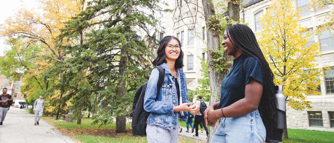 Two female students meeting in the green open space on campus. 