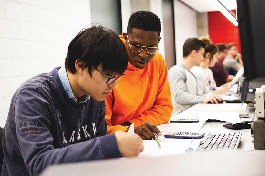 Two male students studying together in a computer lab.