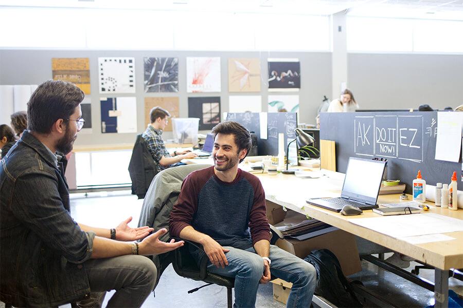 Two students talking to each other in an art studio.