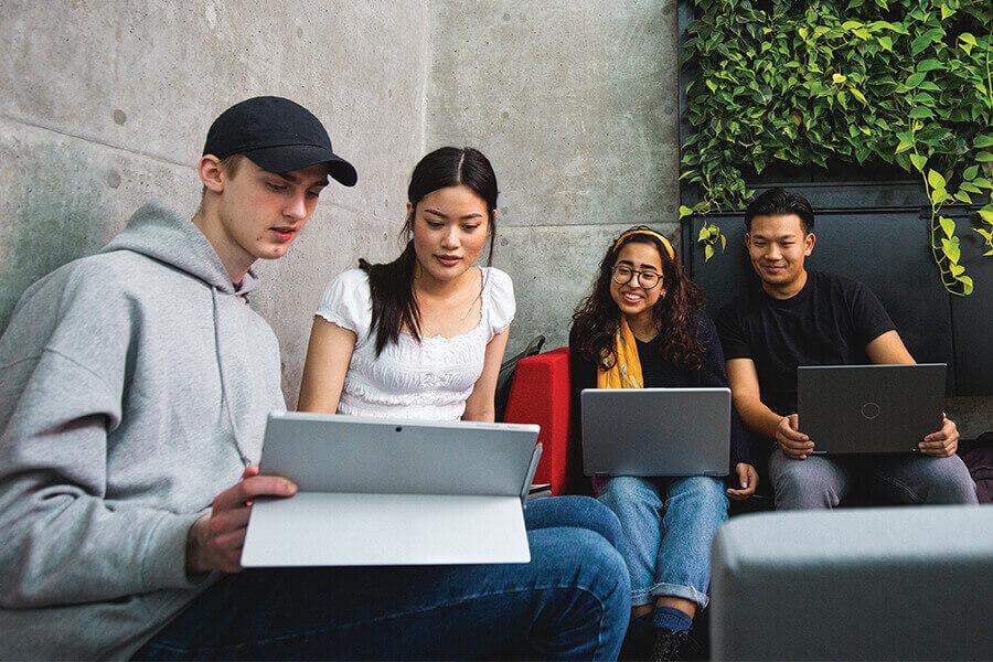 A multicultural group of university students studying together on a bench. 