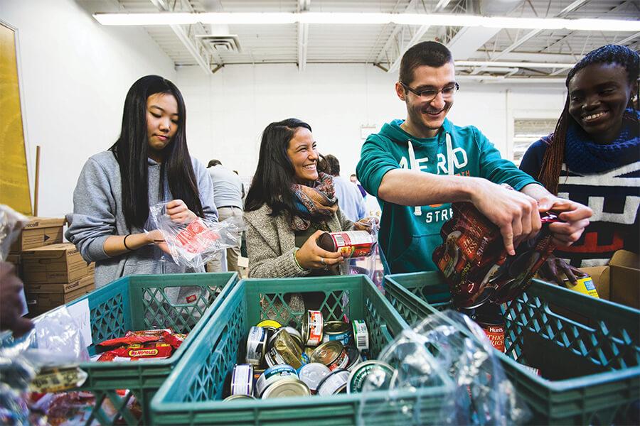 A group of college students working to put a food basket together.