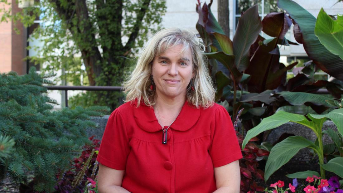Photo of Dr. Kelley Main seated outdoors with plants in the background
