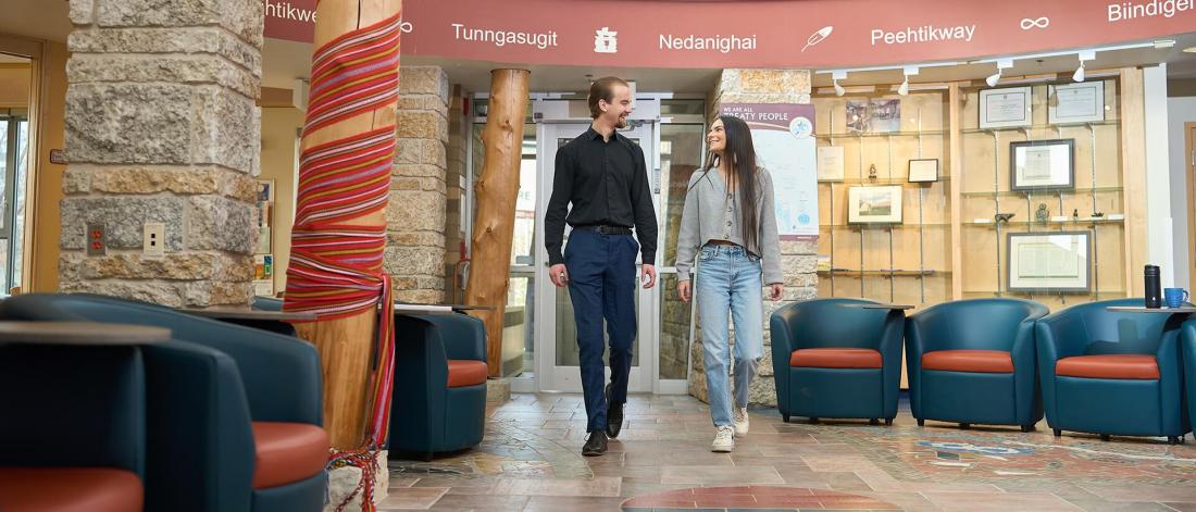 An image of two people smiling while walking into Migizii Agamik at University of Manitoba