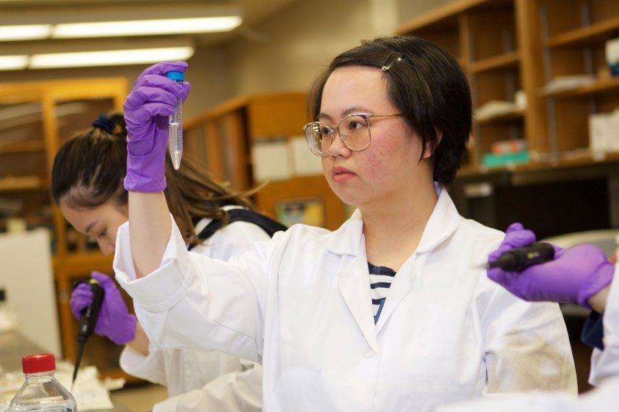 A student examining a vial in a lab.