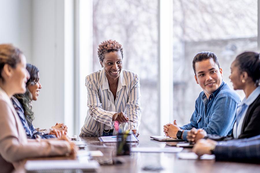 Business meeting with smiling woman standing at the top of the desk