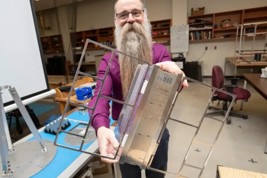 Dr. Philip Ferguson holds a satellite in his lab. 