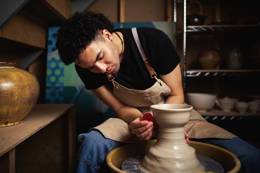 A person works at a potter's wheel.