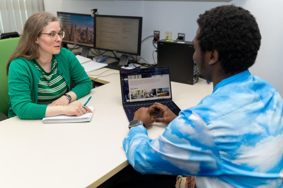 A librarian helping a student working on a laptop in an office