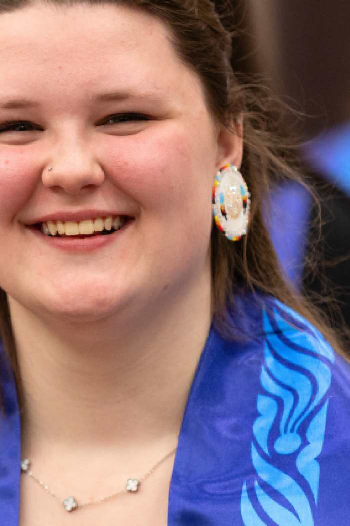 A group of smiling graduates wearing blue stoles.