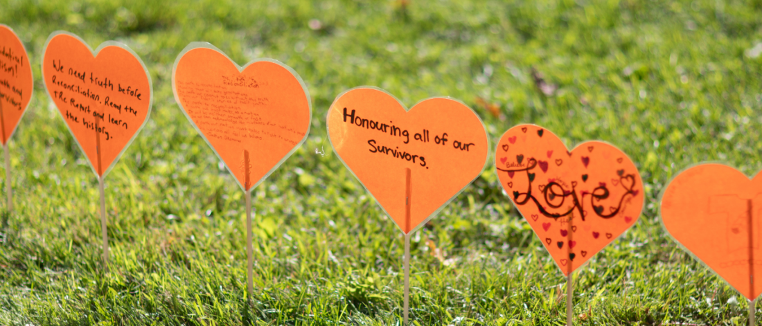Close-up of orange heart messages on grass.