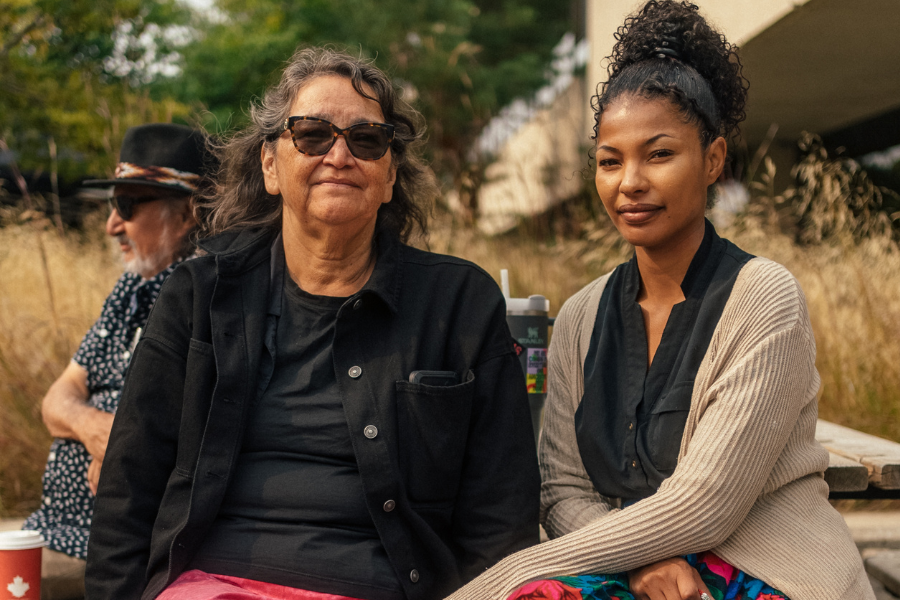A women smiling while sitting on an outdoor bench with Elder Karen.