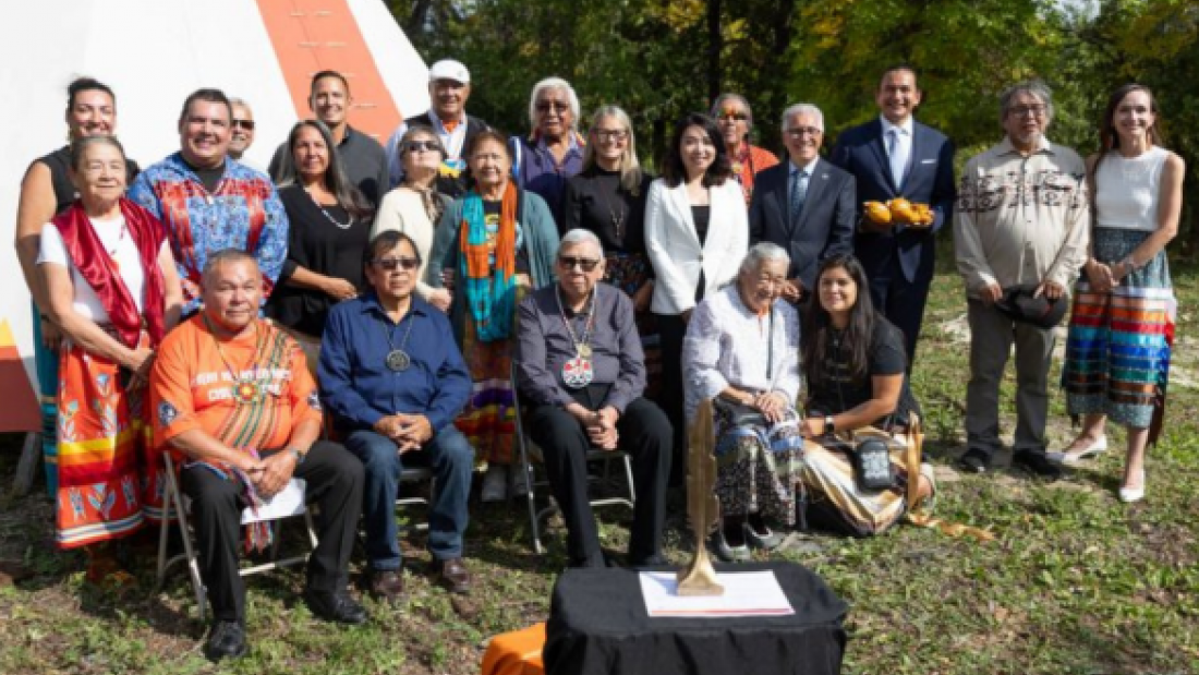 Group photo of Elders, community members, and university leaders outdoors beside a tipi.