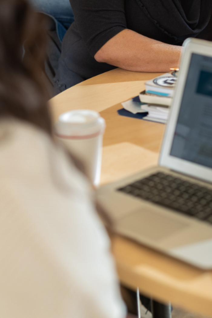 Student meeting with a staff member while working on a laptop.