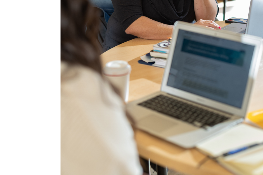 Student meeting with a staff member while working on a laptop.