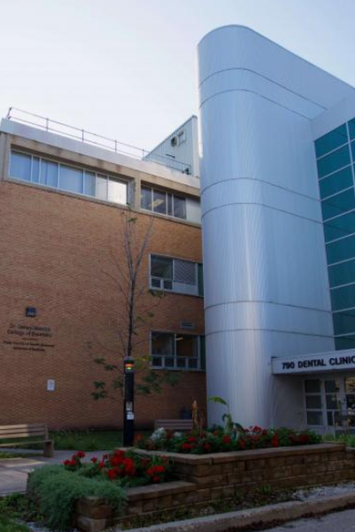 Exterior view of the Rady Faculty of Health Sciences building with “790 Dental Clinic” entrance, trees and flowers along the sidewalk.